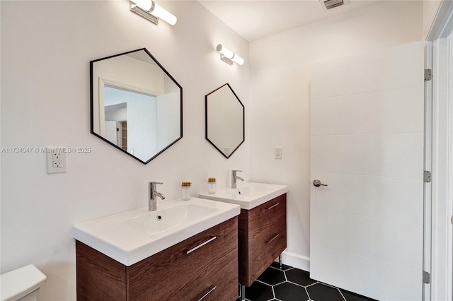 bathroom with a sink, two vanities, toilet, and tile patterned floors