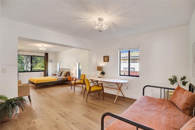 bedroom with light wood-type flooring, an inviting chandelier, and baseboards