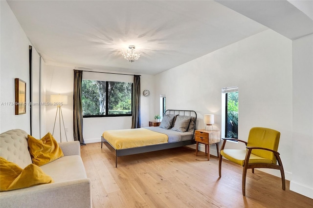 bedroom with light wood-type flooring, baseboards, and a notable chandelier