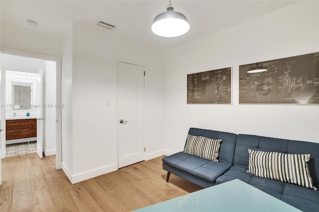 living room with baseboards, visible vents, and wood finished floors