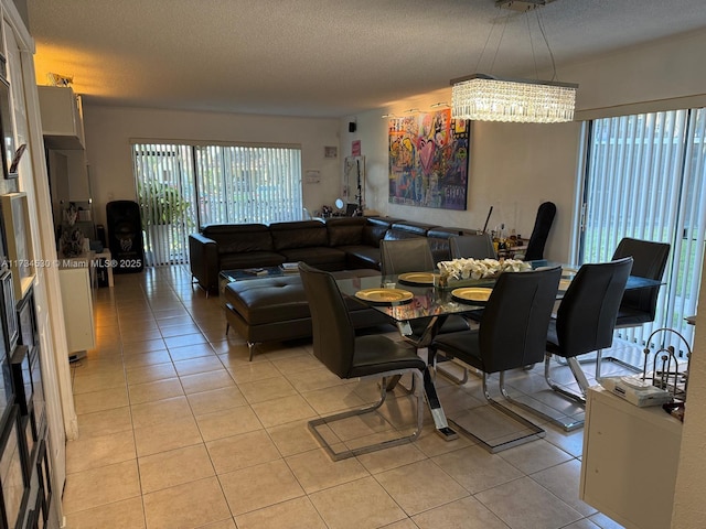 dining area with an inviting chandelier, light tile patterned floors, and a textured ceiling