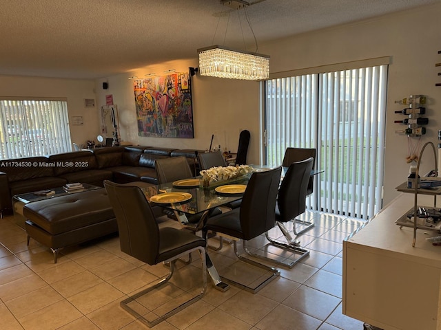 dining area with an inviting chandelier, light tile patterned floors, and a textured ceiling