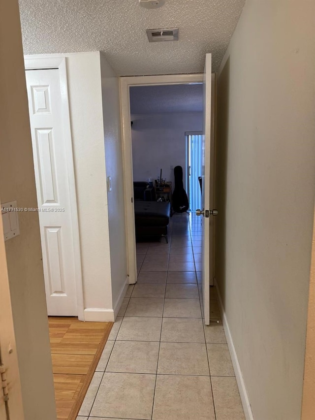 corridor with light tile patterned flooring and a textured ceiling