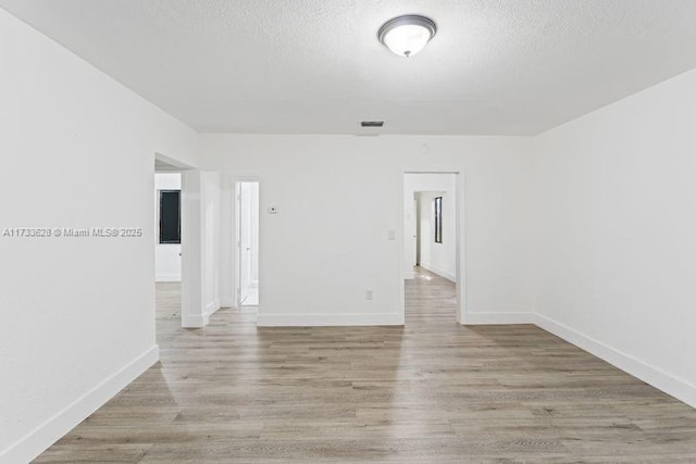 empty room featuring a textured ceiling and light hardwood / wood-style flooring