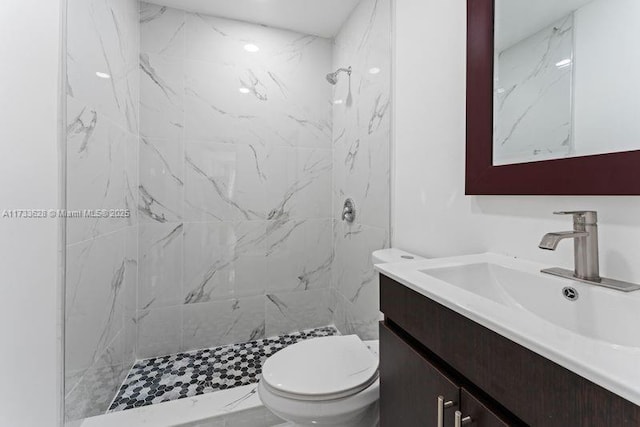 bathroom with vanity, toilet, and a tile shower