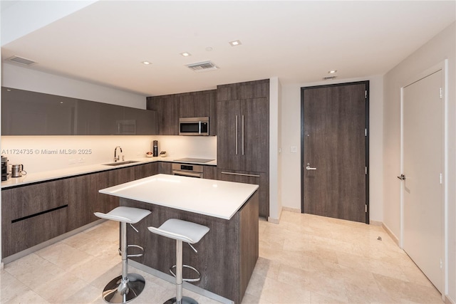 kitchen with appliances with stainless steel finishes, a kitchen breakfast bar, a center island, and sink