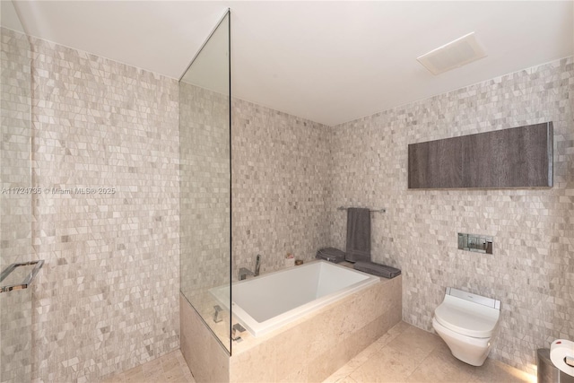 bathroom featuring toilet, independent shower and bath, tile patterned flooring, and tile walls