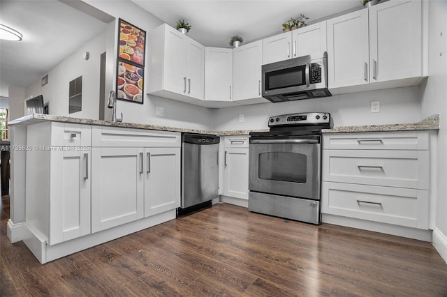 kitchen with light stone countertops, appliances with stainless steel finishes, dark wood-type flooring, and white cabinets