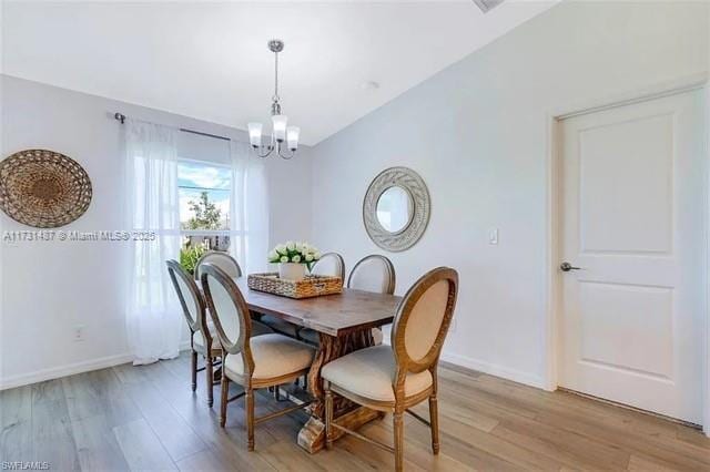 dining area featuring vaulted ceiling, light hardwood / wood-style floors, and a chandelier