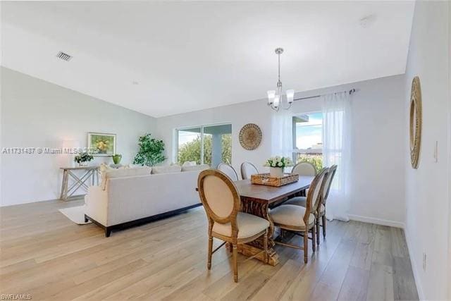 dining room featuring lofted ceiling, a wealth of natural light, a notable chandelier, and light hardwood / wood-style floors