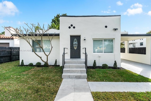 view of front facade featuring fence, a front lawn, and stucco siding