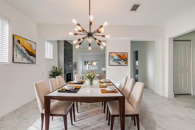 dining room with a notable chandelier, a large fireplace, visible vents, baseboards, and marble finish floor