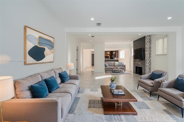 living area featuring a tile fireplace, visible vents, and recessed lighting