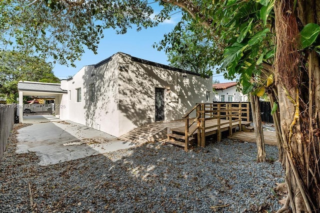 view of home's exterior featuring fence, a wooden deck, and stucco siding