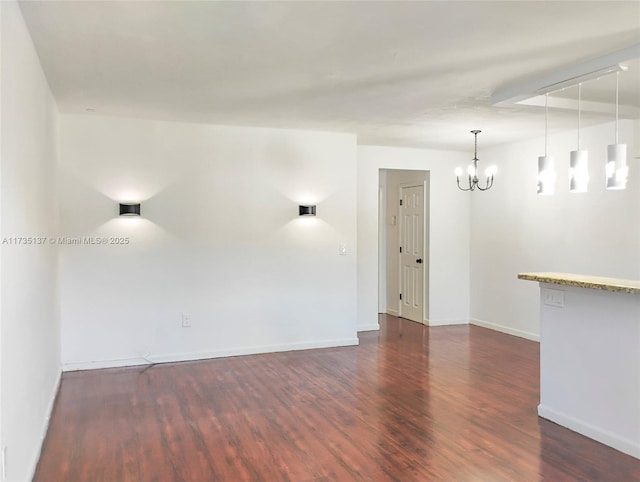 spare room featuring dark hardwood / wood-style floors and an inviting chandelier