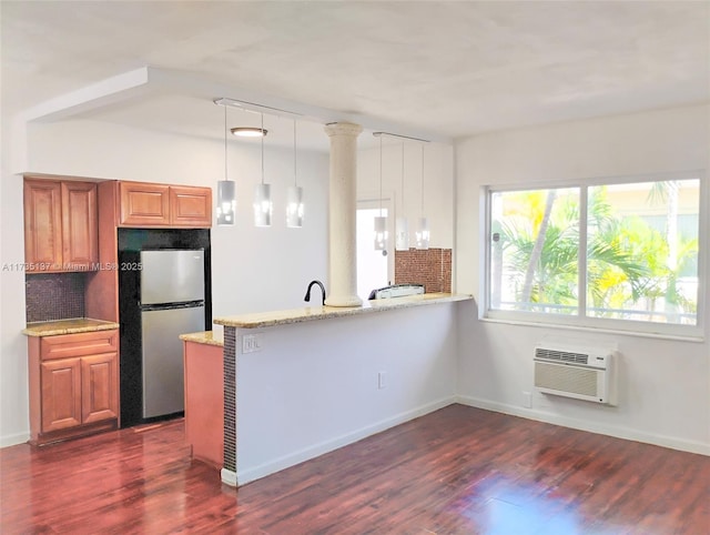 kitchen with decorative light fixtures, stainless steel fridge, a wall unit AC, and kitchen peninsula