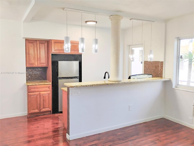 kitchen featuring pendant lighting, dark wood-type flooring, kitchen peninsula, and stainless steel refrigerator