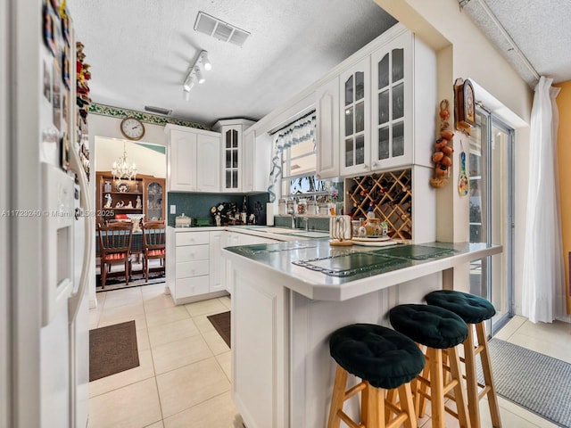 kitchen with tasteful backsplash, light tile patterned floors, white cabinets, and a kitchen breakfast bar