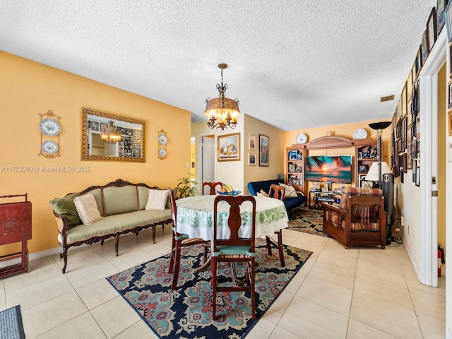 dining area with a notable chandelier, lofted ceiling, a textured ceiling, and light tile patterned floors