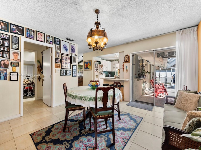 dining room with an inviting chandelier, a textured ceiling, and light tile patterned flooring