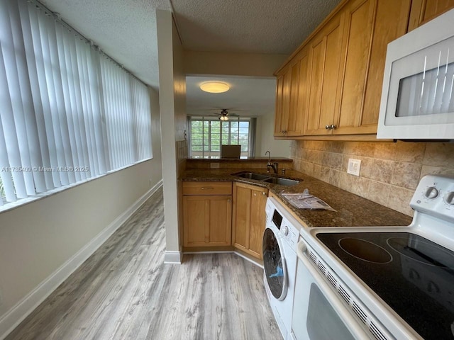 kitchen with washer / dryer, sink, tasteful backsplash, light hardwood / wood-style flooring, and white appliances