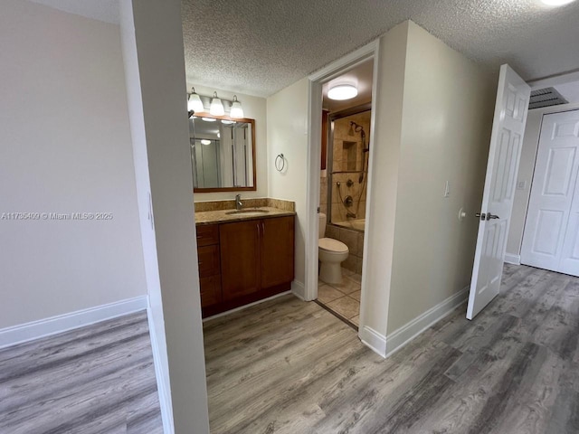 full bathroom with tiled shower / bath combo, hardwood / wood-style floors, a textured ceiling, and toilet