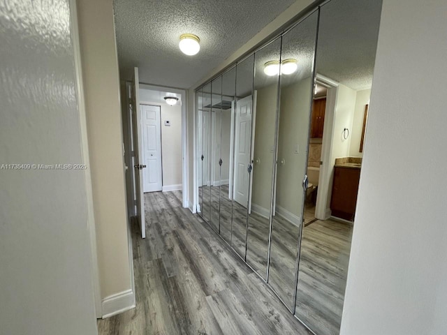 hall with wood-type flooring and a textured ceiling