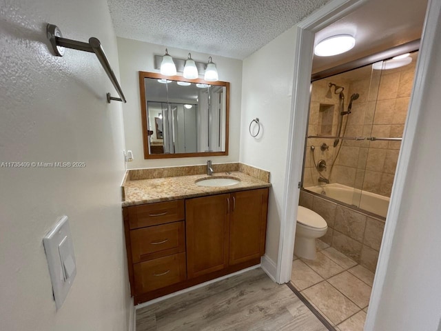 full bathroom featuring toilet, a textured ceiling, vanity, tiled shower / bath combo, and hardwood / wood-style floors