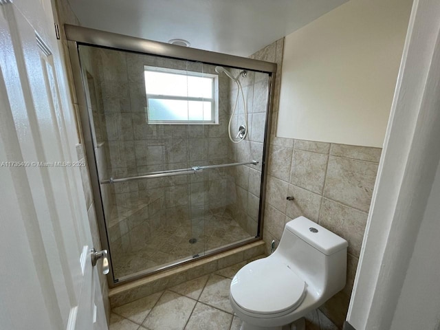 bathroom featuring toilet, an enclosed shower, tile patterned flooring, and tile walls