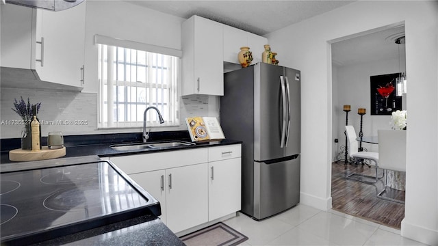 kitchen with stainless steel refrigerator, backsplash, sink, and white cabinets