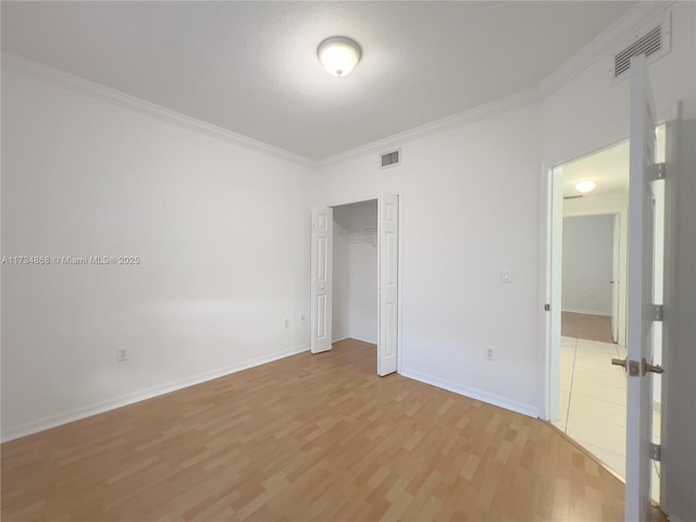 unfurnished bedroom with crown molding, wood-type flooring, and a closet