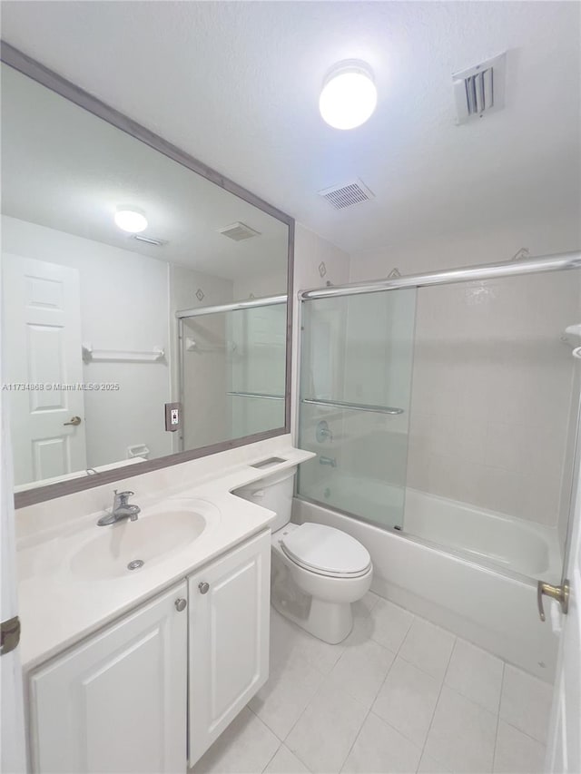 full bathroom featuring vanity, bath / shower combo with glass door, tile patterned floors, and toilet