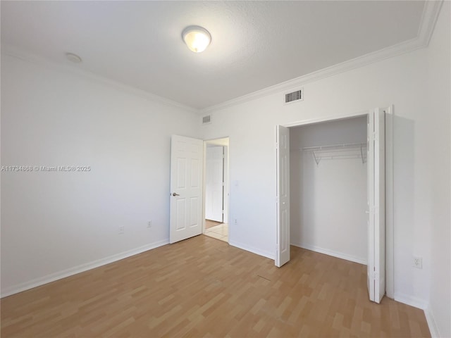 unfurnished bedroom with crown molding, light hardwood / wood-style floors, and a closet