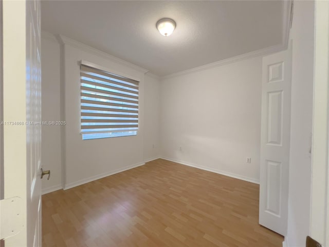 empty room with crown molding and light wood-type flooring