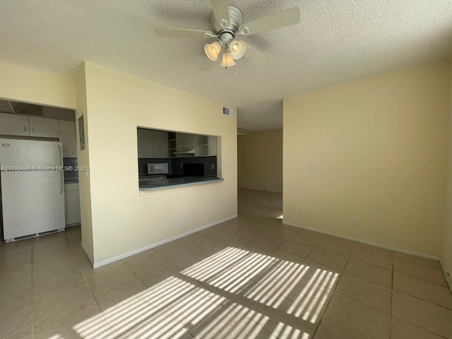 unfurnished living room with light tile patterned floors, a textured ceiling, and ceiling fan