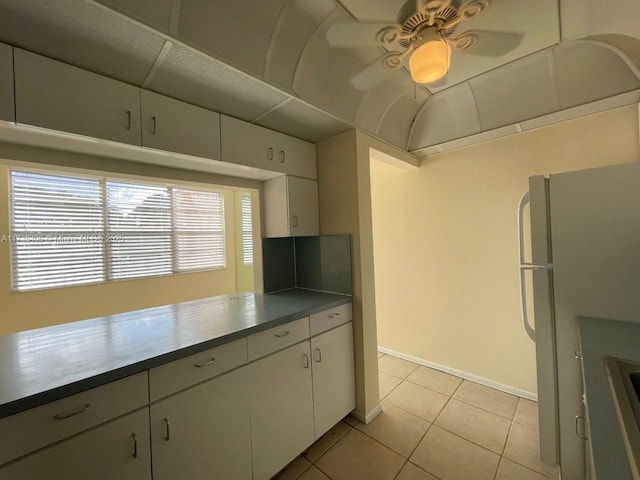 kitchen with ceiling fan, light tile patterned floors, white fridge, and white cabinets