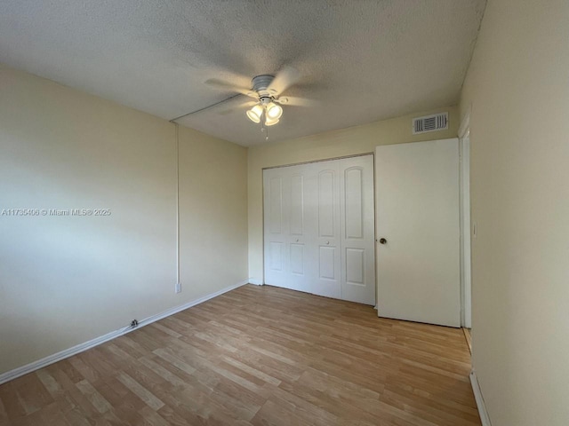 unfurnished bedroom featuring a closet, ceiling fan, a textured ceiling, and light hardwood / wood-style flooring
