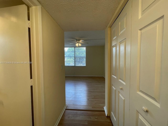 hallway with wood-type flooring and a textured ceiling