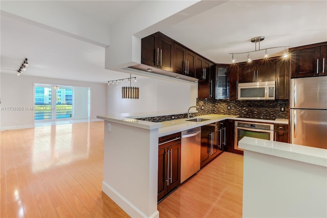 kitchen featuring hanging light fixtures, backsplash, dark brown cabinets, stainless steel appliances, and light hardwood / wood-style floors