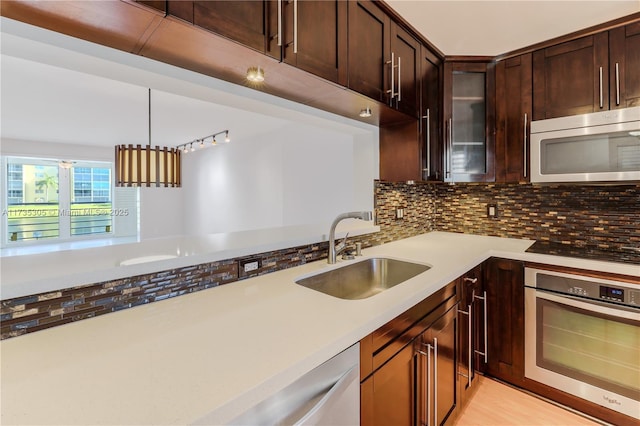 kitchen with dark brown cabinetry, sink, appliances with stainless steel finishes, pendant lighting, and backsplash