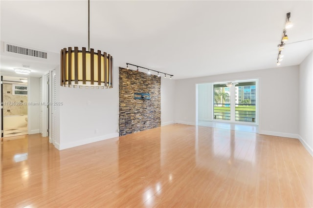 unfurnished living room with rail lighting and light hardwood / wood-style floors