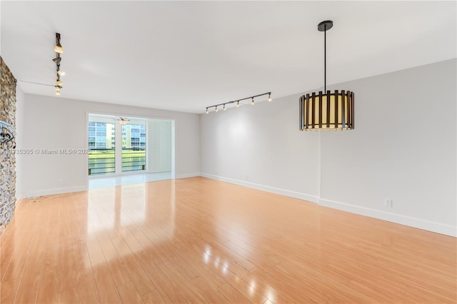 unfurnished room featuring track lighting and light wood-type flooring