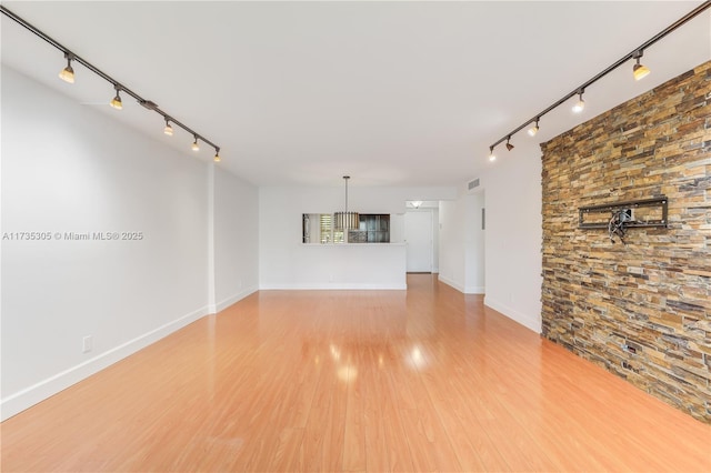 unfurnished living room featuring wood-type flooring and rail lighting