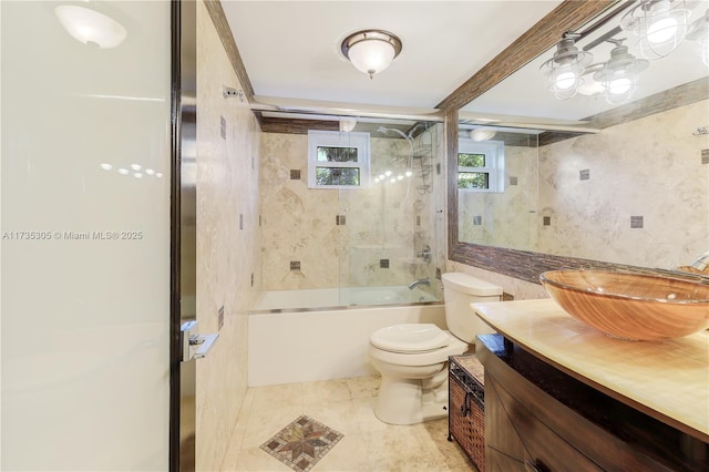 full bathroom featuring shower / bath combination with glass door, tile walls, tile patterned flooring, vanity, and toilet