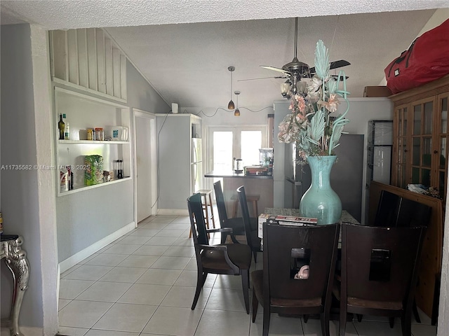 tiled dining area with a textured ceiling, vaulted ceiling, and ceiling fan