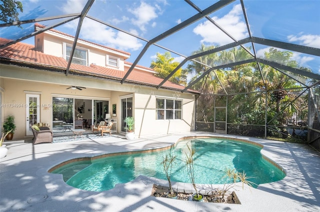 outdoor pool featuring glass enclosure, a patio, and a ceiling fan