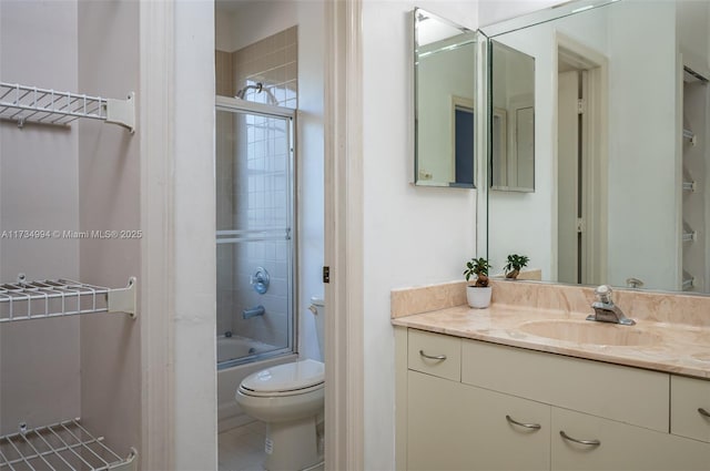 bathroom featuring bath / shower combo with glass door, toilet, and vanity