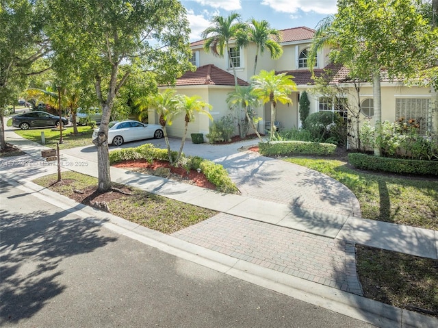 view of front of home featuring stucco siding, a tiled roof, and decorative driveway