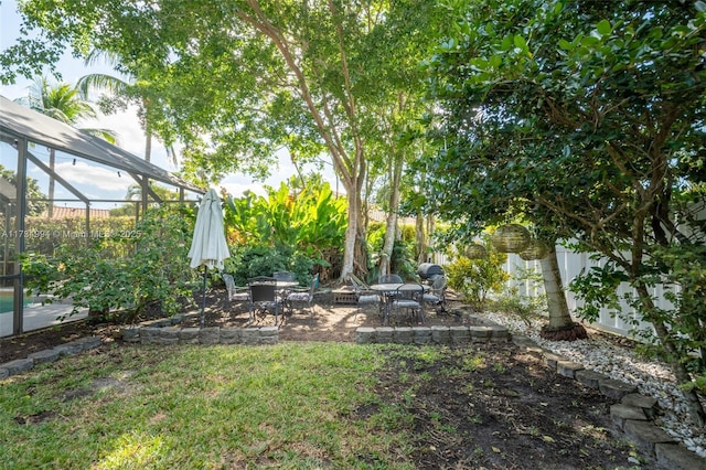 view of yard featuring a lanai, a patio, and fence