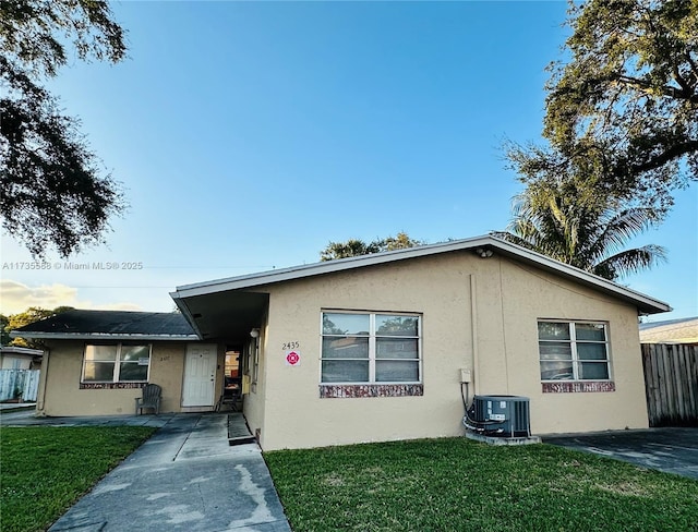 view of front of home with central AC and a front yard